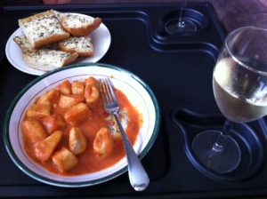 Gnocchi in vodka sauce, with glass of white wine and plate of garlic bread
